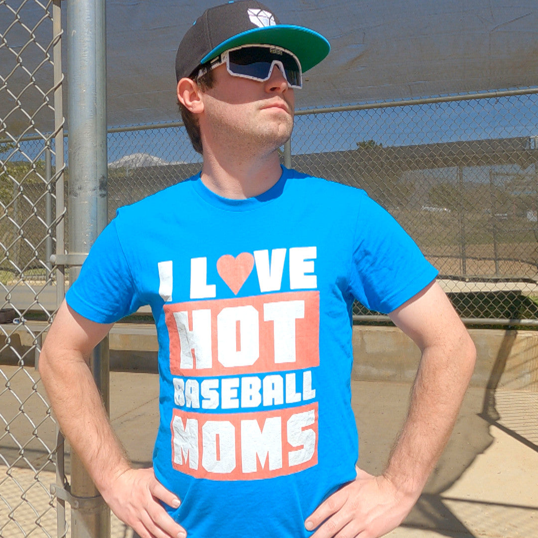 A baseball coach wearing a Web Gem baseball hat, sunglasses, and a bright blue shirt that says "I love hot baseball moms."