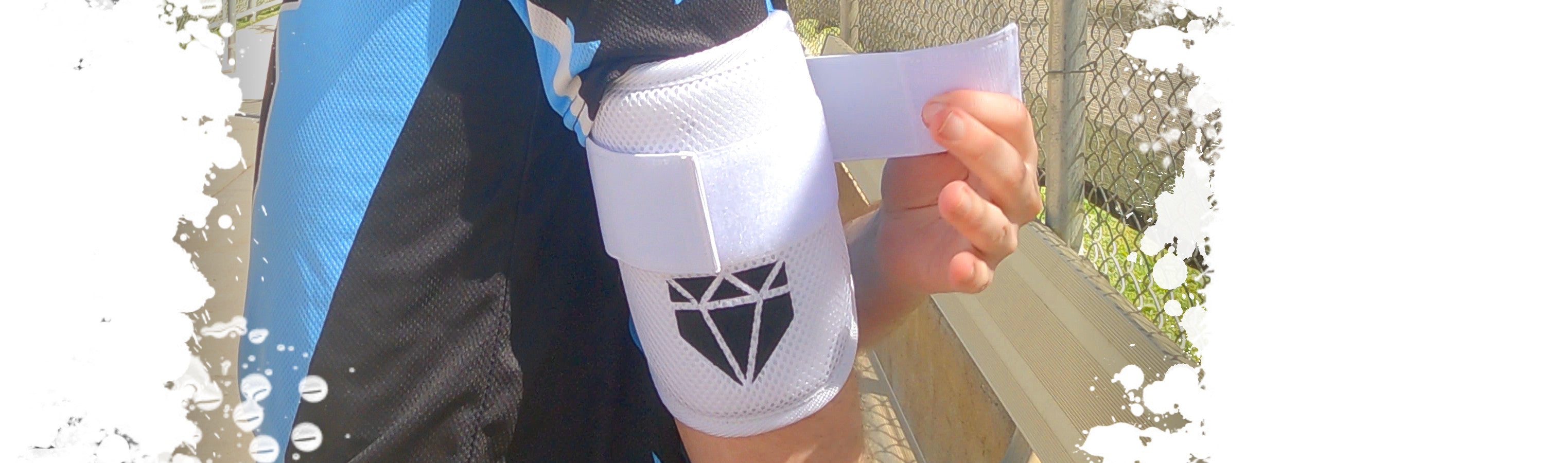 A baseball player adjusting the elastic Velcro strap on the Moonshot White Baseball Elbow Guard from Web Gem Apparel while in the dugout.